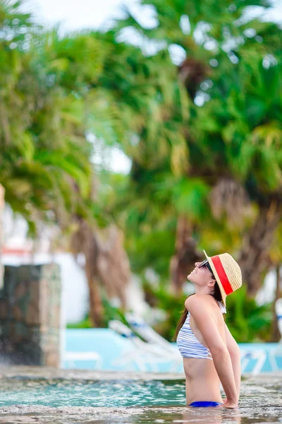 Beautiful young woman relaxing in swimming pool. Back view of girl in outdoor pool at luxury hotel — Stock Photo, Image