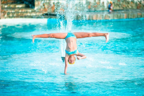 Bonne petite fille profiter des vacances dans la piscine. Enfant sportif faisant roue sur le bord de la piscine — Photo