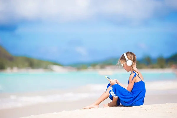 Menina ouvindo a música por fones de ouvido na praia — Fotografia de Stock