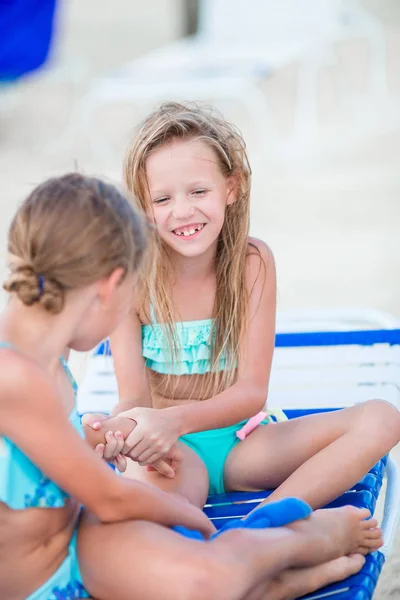 Kleine Mädchen amüsieren sich am tropischen Strand und spielen zusammen auf der Sonnenliege — Stockfoto