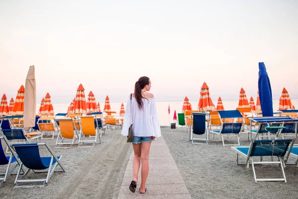 Mujer joven en la playa en vacaciones europeas en la costa de Liguria en la puesta del sol —  Fotos de Stock