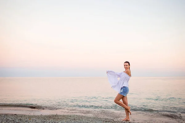 Jonge vrouw aan het strand in Europese vakantie aan de Ligurische kust in de zonsondergang — Stockfoto