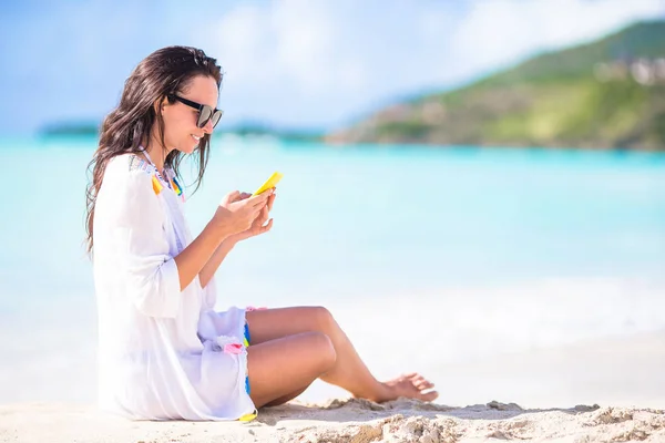 Ung kvinna med smartphone under tropisk strandsemester. Vacker flicka på stranden med mobiltelefon på karibiska ön — Stockfoto