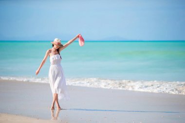 Beyaz kum tropikal plaj üzerinde genç güzel kadın. Deniz arka plan beyaz elbiseli şapkalı beyaz kız