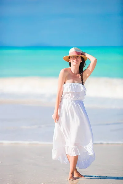 Mooie jongedame op witte zand tropisch strand. Kaukasische meisje met hoed in jurk achtergrond de zee — Stockfoto
