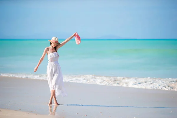Νεαρή όμορφη γυναίκα στην τροπική παραλία με λευκή άμμο. Καυκάσιος κορίτσι με καπέλο σε φόντο λευκό φόρεμα στη θάλασσα — Φωτογραφία Αρχείου
