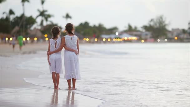 Очаровательные маленькие дети прогуливаются по пляжу с красивым красочным закатом — стоковое видео