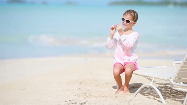 Boldog kislány játékgéppel a kezében a fehér homokos parton. Gyerek játék játék a strandon — Stock videók