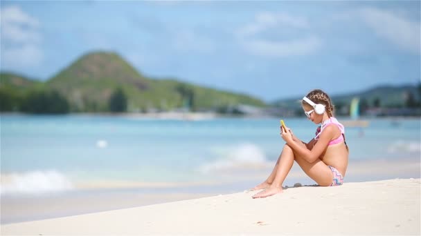 Menina ouvindo música em fones de ouvido na praia — Vídeo de Stock