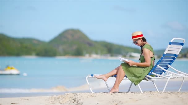 Mujer joven leyendo libro sobre tumbonas durante la playa tropical blanca — Vídeos de Stock