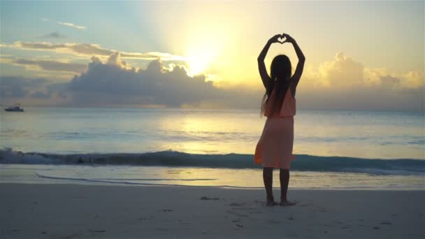 Adorável menina feliz ter um monte de diversão na praia branca ao pôr do sol . — Vídeo de Stock