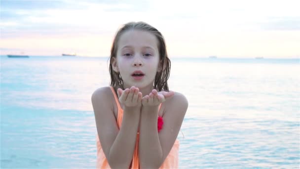 Entzückendes kleines Mädchen am Strand, das am Abend eine Menge Spaß hat. glückliches Kind blickt auf Kamera Hintergrund schönen Himmel und Meer — Stockvideo