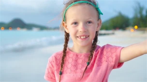 Adorable niñita haciendo selfie en la playa tropical blanca. MOCIÓN LENTA — Vídeos de Stock