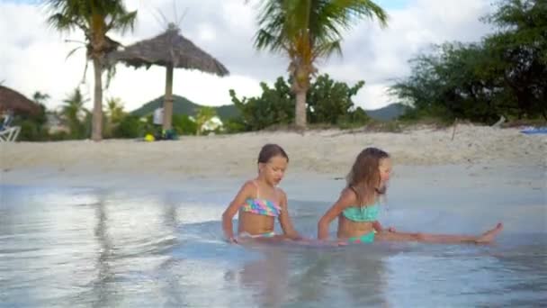 Schattige meisjes spelen met zand op het strand. Kinderen zitten in ondiep water en het maken van een zandkasteel — Stockvideo