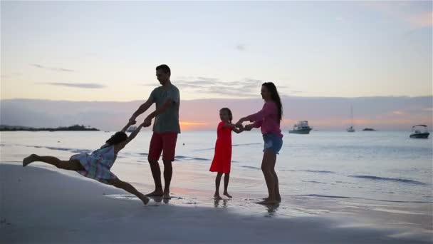 Gelukkig mooi familie op een strand tijdens de zomervakantie. Familie van vier veel plezier bij zonsondergang op het strand — Stockvideo