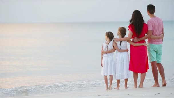 Glückliche schöne Familie am Strand. Rückansicht von Eltern und Kindern bei Sonnenuntergang — Stockvideo