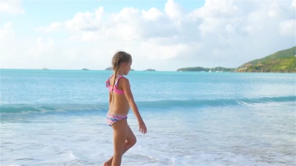 Маленькая активная девочка делает колесики на пляже на закате. Медленное движение — стоковое видео