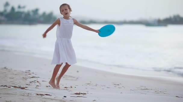 Dziewczynka bawi się latający dysk na plaży o zachodzie słońca — Wideo stockowe