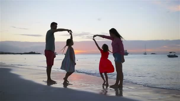 Οι γονείς και τα δύο παιδιά έχουν πολλή διασκέδαση στην παραλία το ηλιοβασίλεμα. Τετραμελή οικογένεια με αγάπη, όμορφες και χαρούμενες. — Αρχείο Βίντεο
