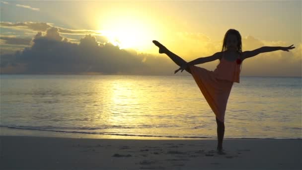 Silhuetten av bedårande liten flicka på stranden vid solnedgången. Slow Motion — Stockvideo