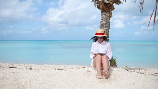 Ung kvinna läser bok under tropisk vit strand — Stockvideo