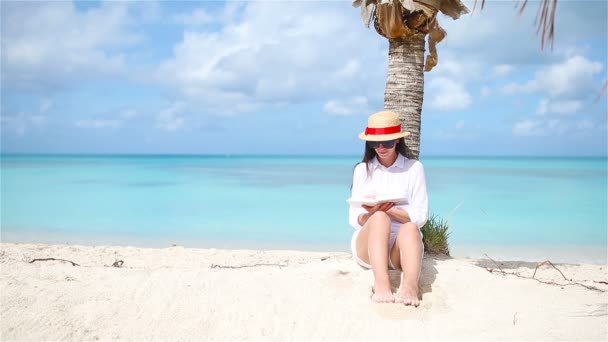 Fiatal nő olvasás könyv alatt trópusi fehér strand — Stock videók