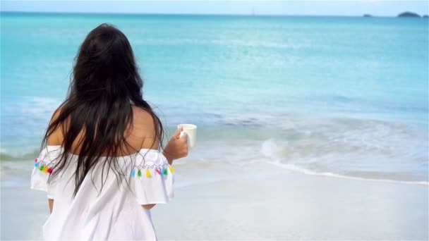 Mujer joven con café caliente disfrutando de vistas a la playa. Hermosa chica en cámara lenta de vídeo — Vídeos de Stock