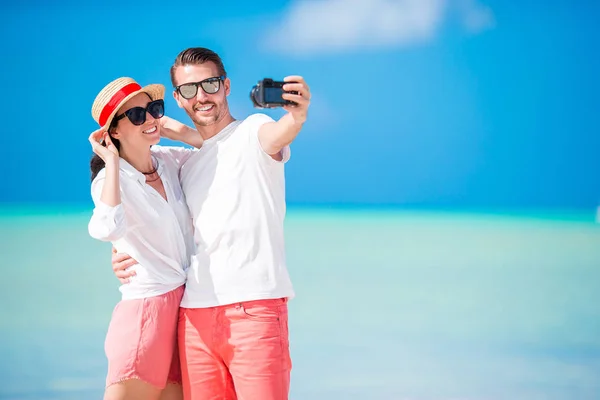 Una pareja tomando selfies en la playa. Turistas personas que toman fotos de viaje en vacaciones de verano . — Foto de Stock