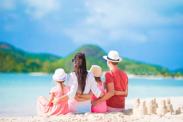 Tropik beyaz sahilde kumdan kale yapan dört kişilik bir aile. — Stok fotoğraf