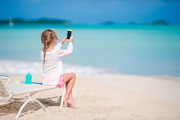 Kleine meisje het maken van video of foto met door haar camera zittend op de zonnebank — Stockfoto