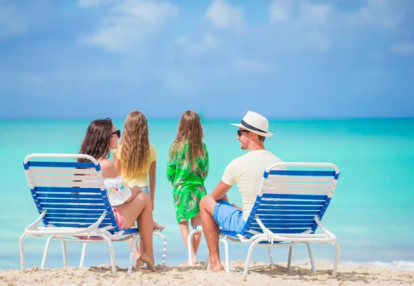 Dört sahilde mutlu güzel aile. Ebeveynler şezlong ve çocuklar eğleniyor sahilde rahatlatıcı — Stok fotoğraf
