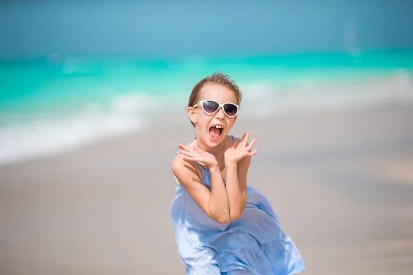 Porträt eines glücklichen liebenswerten Kindes, das vor dem Hintergrund der Kamera den schönen Himmel und das Meer betrachtet. kleines Mädchen mit Sonnenbrille lächelt und genießt ihren Urlaub — Stockfoto
