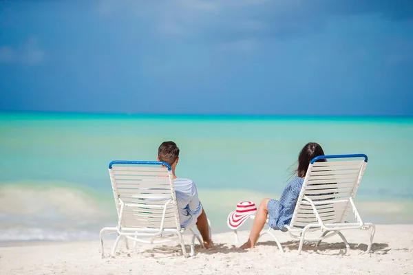 Två glada människor att ha kul på stranden, sitter på bekväm solsäng — Stockfoto