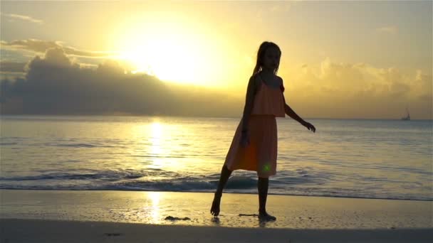 Очаровательная счастливая маленькая девочка получает много удовольствия на белом пляже на закате. Медленное движение — стоковое видео