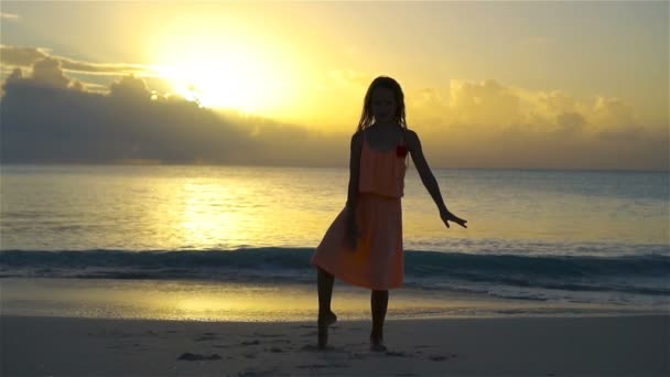 Silhueta de adorável menina ativa na praia branca ao pôr do sol. LOW MOTION — Vídeo de Stock