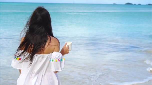 Νεαρή γυναίκα με φλιτζάνι χαλαρωτικό τσάι στην παραλία — Αρχείο Βίντεο
