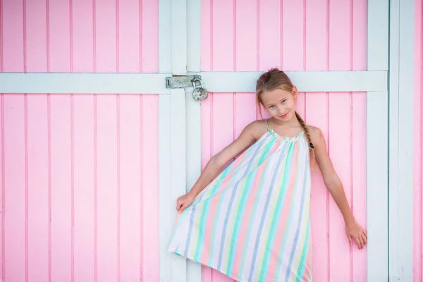 Adorable niña al aire libre cerca de la casa tradicional caribeña de color rosa —  Fotos de Stock