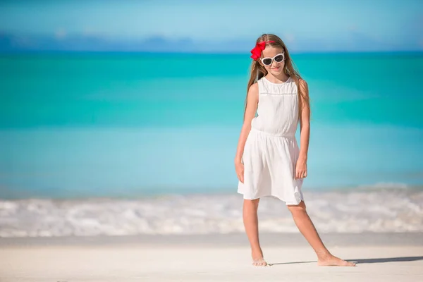Schöne kleine Mädchen in weißem Kleid am Strand Spaß haben. — Stockfoto