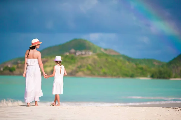 Beautiful mother and daughter on Caribbean beach with amazing rainbow on background — Stock Photo, Image