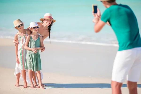 Muž s fotografii své rodiny na pláži. Rodinná pláž dovolená — Stock fotografie