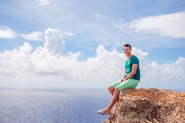Young man enjoying breathtaking views from Shirley Heights on Antigua island in Caribbean clipart