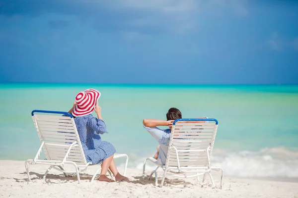 Happy family relaxing on a tropical beach on the beach chairs — Stock Photo, Image