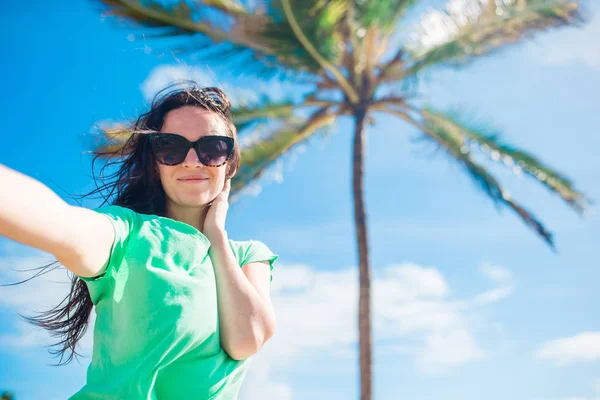 Ung kvinna tar selfie porträtt bakgrund palmträd på stranden — Stockfoto