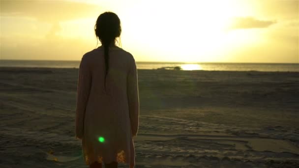 Чарівна щаслива маленька дівчинка гуляє на білому пляжі на заході сонця — стокове відео