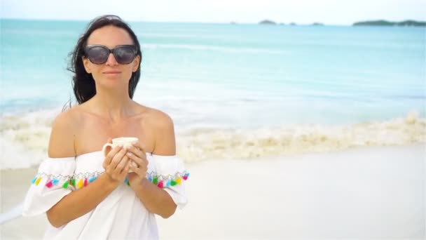 Mujer joven con café caliente disfrutando de vista a la playa . — Vídeos de Stock