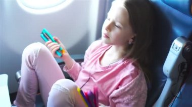 Sevimli küçük kız bir uçakla seyahat. Uçak penceresinde yakınındaki dizüstü bilgisayar ile şirin çocuk