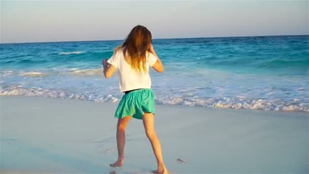 Adorable niña feliz en la playa blanca al atardecer — Vídeo de stock