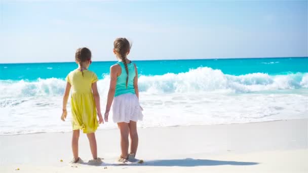 Adorables niñas tienen un montón de diversión en la playa. Dos hermosos niños corriendo y salpicando en aguas poco profundas — Vídeos de Stock