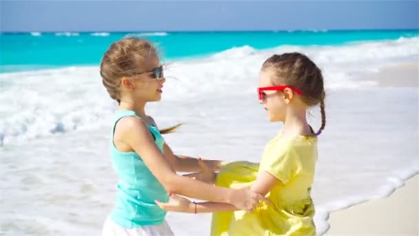 Meisjes die plezier hebben op het tropische strand en samen spelen. Schattige zusjes aan het strand tijdens de zomervakantie — Stockvideo