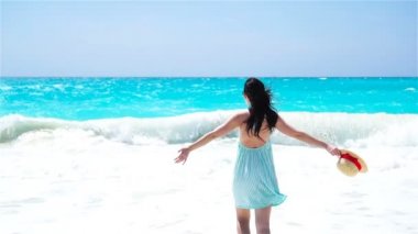Beyaz kum tropikal plaj üzerinde genç güzel kadın. Arkadan görünüşü ile şapka arka plan deniz beyaz kız